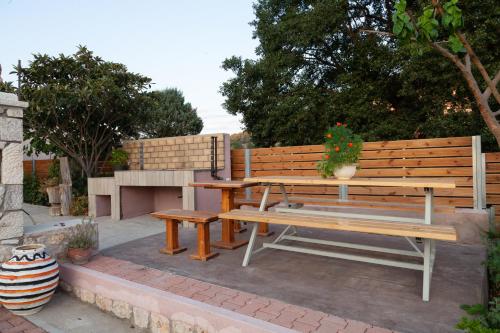 a wooden bench and picnic table with a potted plant at Tsoutsis Apartments in Marantochori