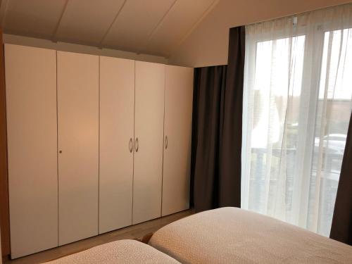 a bedroom with white cabinets and a window at Knus appartement met zicht op zeepolder in De Haan
