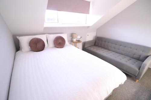 a bedroom with a white bed and a couch at Amaya Four - Sleeps 5 - 1 bed apartment - Newly renovated- Close to town centre -Grantham in Grantham