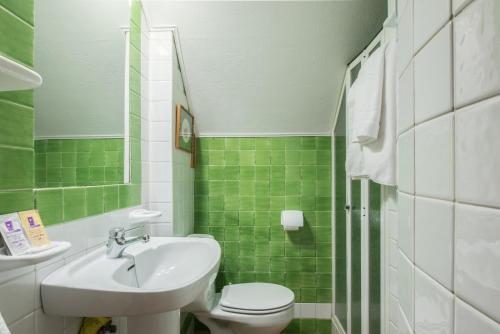 a green and white bathroom with a sink and a toilet at Apartamento Ameto en la plaza Pradollano"Junto al telecabina Borreguiles" in Sierra Nevada