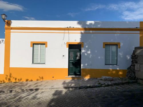 a white and orange building with a green door at Casa do Arco - Beja in Beja