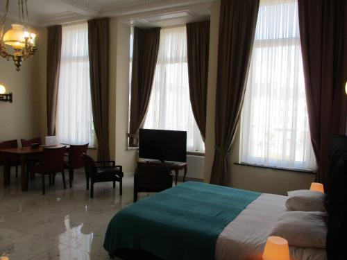 a hotel room with a bed and a dining room at Hotel de la Gare Aalst in Aalst