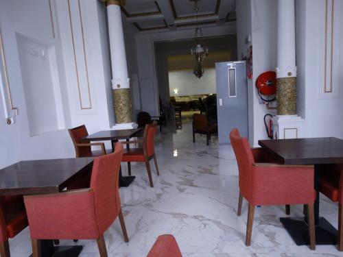 a dining room with tables and chairs and a refrigerator at Hotel de la Gare Aalst in Aalst