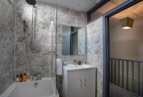 La salle de bains est pourvue d'une baignoire, d'un lavabo et d'une douche. dans l'établissement Beautiful river balcony cottage in heart of historic sandwich, à Kent