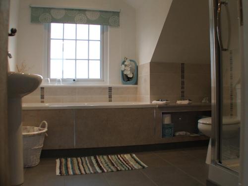 La salle de bains est pourvue d'une baignoire, de toilettes et d'une fenêtre. dans l'établissement Pen Llyn Bed and Breakfast, à Dinas