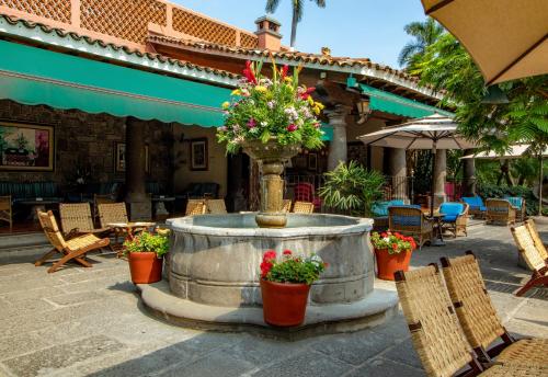 a fountain in a courtyard with chairs and flowers at Las Mañanitas in Cuernavaca