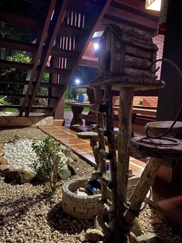 a small garden with a bird house and a bench at Hostel Trópico de Capricórnio - Tenório in Ubatuba