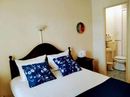 a bedroom with a bed with blue and white pillows at Corações Unidos "A Pensão" in Alcobaça