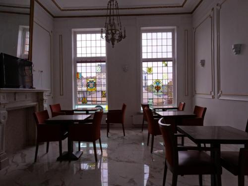 a dining room with tables and chairs and stained glass windows at Hotel de la Gare Aalst in Aalst