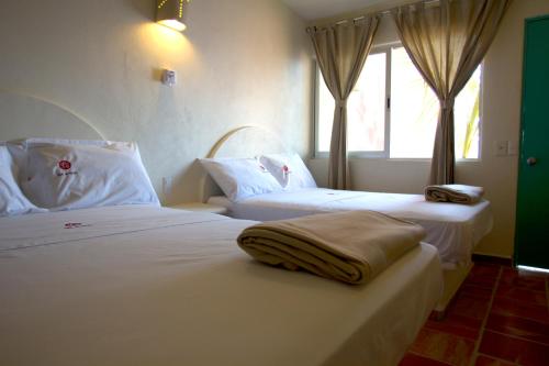 a hotel room with two beds and a window at Bungalows Las Arenas in San Patricio Melaque