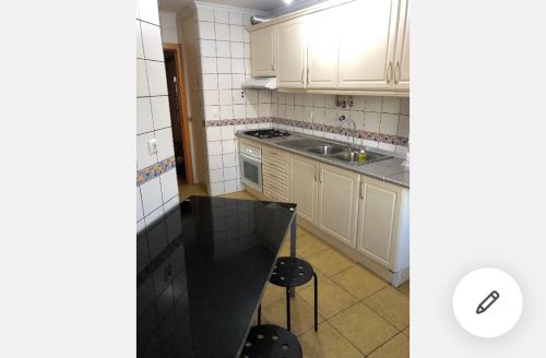 une cuisine avec des placards blancs et un comptoir noir dans l'établissement Wonderful apartament Lisbon, à Montijo