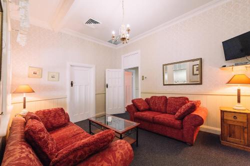 a living room with two red couches and a table at Fitzroy Motor Inn in Grafton