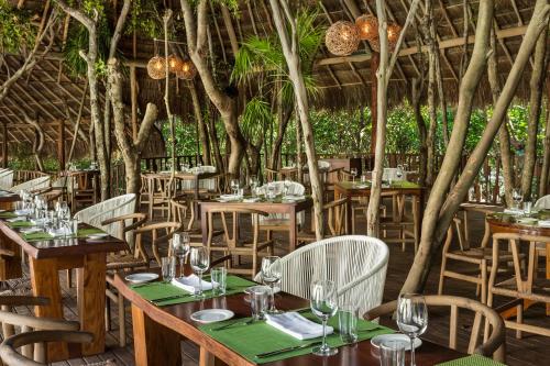 a restaurant with wooden tables and chairs and trees at The Fives Beach Hotel & Residences - All Senses Inclusive in Playa del Carmen
