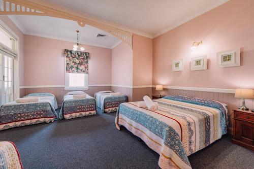 a bedroom with four beds and a window at Fitzroy Motor Inn in Grafton