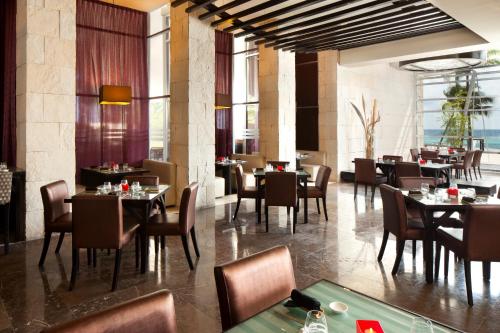 a dining room with tables and chairs and windows at The Fives Beach Hotel & Residences - All Senses Inclusive in Playa del Carmen