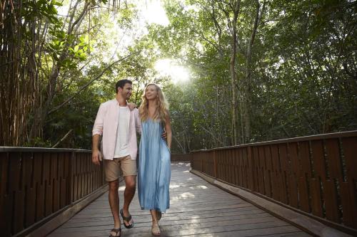 a man and a woman walking on a bridge at The Fives Beach Hotel & Residences - All Senses Inclusive in Playa del Carmen