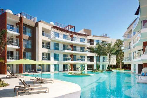 una imagen de una piscina frente a un edificio en The Fives Beach Hotel & Residences - All Senses Inclusive en Playa del Carmen