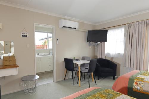 a room with a table and chairs and a bedroom at Aden Motel in Te Anau