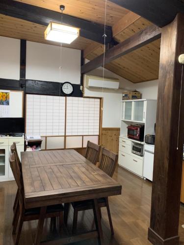 a large kitchen with a wooden table and chairs at 民泊はのこの庭 in Kokuryō