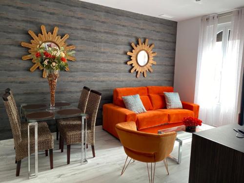 a living room with an orange couch and a table at Apartamentos "El Escondite de Triana" in Seville