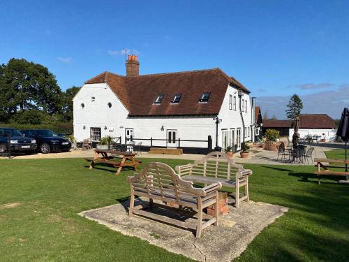 two benches in front of a white building at George & Dragon Country Pub & Hotel Wolverton Townsend in Tadley