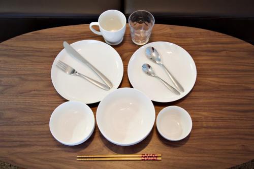 a table with white plates and utensils on it at Vent du Vent302 in Minatogawa
