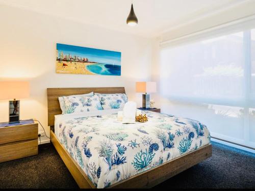 um quarto com uma cama com lençóis azuis e brancos e uma janela em By The Beach Frankston em Frankston