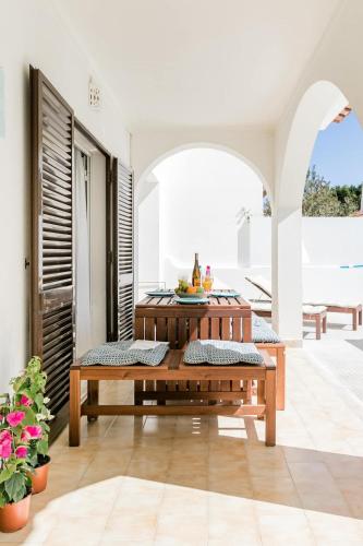 a patio with a wooden table and benches at Beachfront Villa with Private Pool in Manta Rota in Vila Nova De Cacela