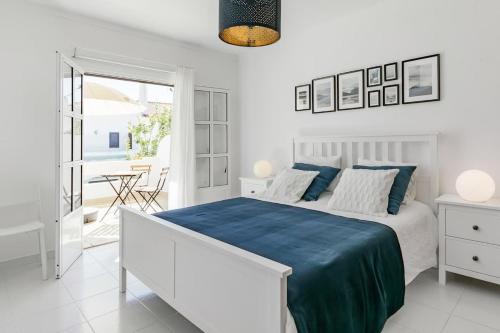 a white bedroom with a bed with a blue blanket at Beachfront Villa with Private Pool in Manta Rota in Vila Nova De Cacela