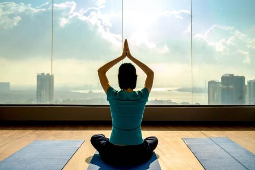 a woman sitting in a yoga pose in front of a window at Holiday Inn Johor Bahru City Centre by IHG in Johor Bahru