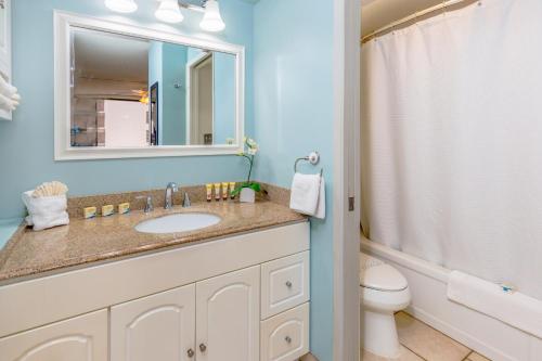 een badkamer met een wastafel, een toilet en een spiegel bij Beach Lover's Haven, Cozy Condo with Ocean Views and Free Parking in Honolulu