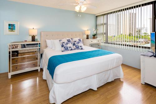 een slaapkamer met een groot bed en een televisie bij Beach Lover's Haven, Cozy Condo with Ocean Views and Free Parking in Honolulu