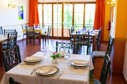a dining room with tables and chairs with plates and glasses at Hotel Rural Serrella in Castell de Castells
