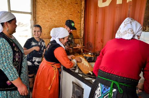 a group of people in a kitchen preparing food at Feel Nomad Yurt Camp in Ak-Say