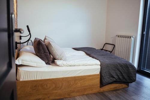 a bed with a wooden frame and pillows on it at Bužinel Estate in Dobrovo