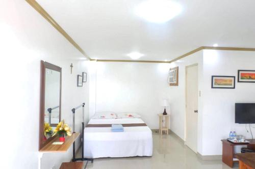 a white room with a bed and a television at Patricios Apartelle Taguig in Manila