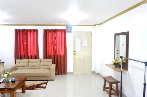 a living room with a couch and red curtains at Patricios Apartelle Taguig in Manila