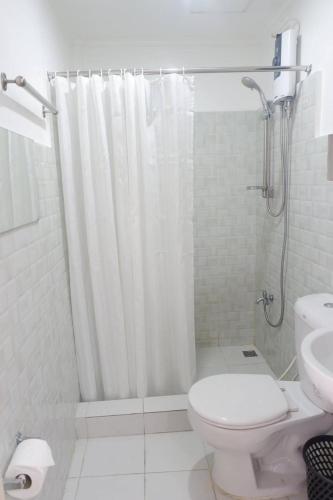 a bathroom with a white shower curtain and a toilet at Patricios Apartelle Taguig in Manila