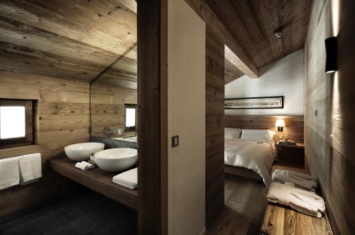 un bagno con due lavandini e un letto in una camera di Chesa Stuva Colani a Madulain