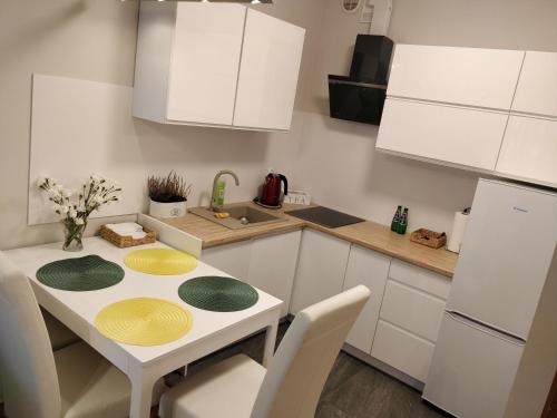 una cucina con armadi bianchi e un tavolo con piatti gialli e verdi di Apartament Cukrownia a Stettino