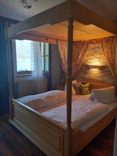 a bedroom with a canopy bed with white sheets at Seepension Knappenhof in Pertisau