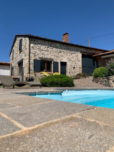 une maison en pierre avec une piscine en face de celle-ci dans l'établissement Domaine des Pierres D Auvergne, à Flat