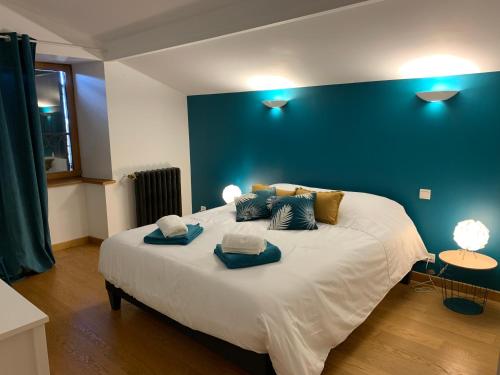 a bedroom with a large bed with a blue wall at Domaine des Pierres D Auvergne in Flat