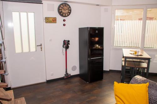 Zimmer mit einem schwarzen Kühlschrank und einem Tisch in der Unterkunft Meublé de tourisme 3 étoiles Loft industriel à Fismes in Fismes