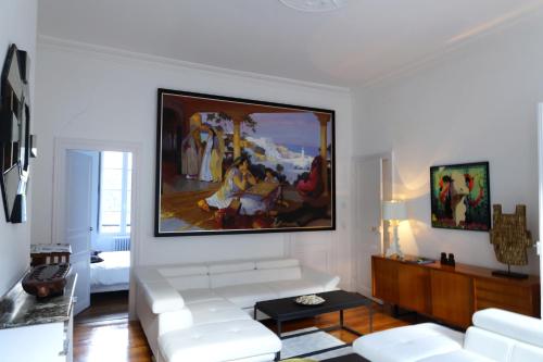 a living room with a white couch and a painting on the wall at Maison Eugénie in Luchon