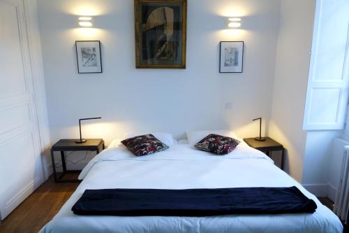 a bedroom with a large white bed with two lamps at Maison Eugénie in Luchon