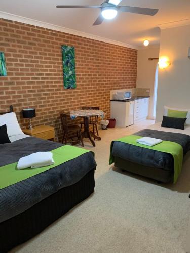 a bedroom with two beds and a brick wall at Motel Views Yackandandah in Yackandandah