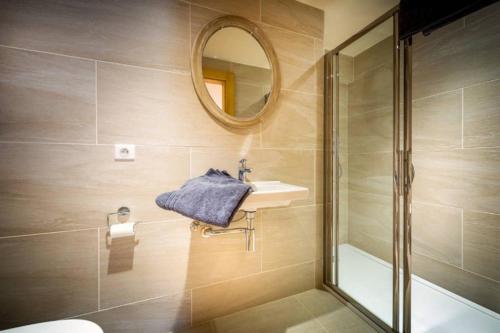a bathroom with a shower and a sink and a mirror at Chalet La Petite Grange in Morzine