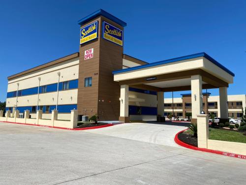 a large building with a parking lot in front of it at Scottish Inn & Suites Houston Willowbrook in Houston