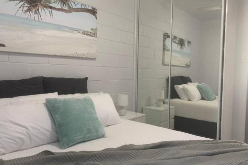 a bedroom with a white bed and a mirror at Walk to Lamberts Beach with Wi-fi and Netflix in Slade Point